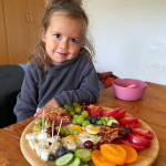 Child sitting at the table with plate of delicious food in front of him.
